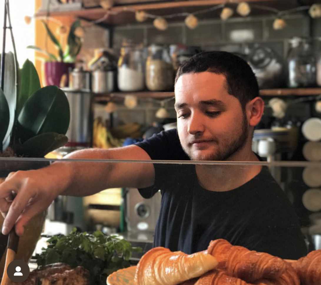 Creative team member at The Yard Café arranging beautiful pastry and cake display